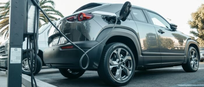 powerbizgroup Modern electric vehicle charging at an outdoor station in daylight.